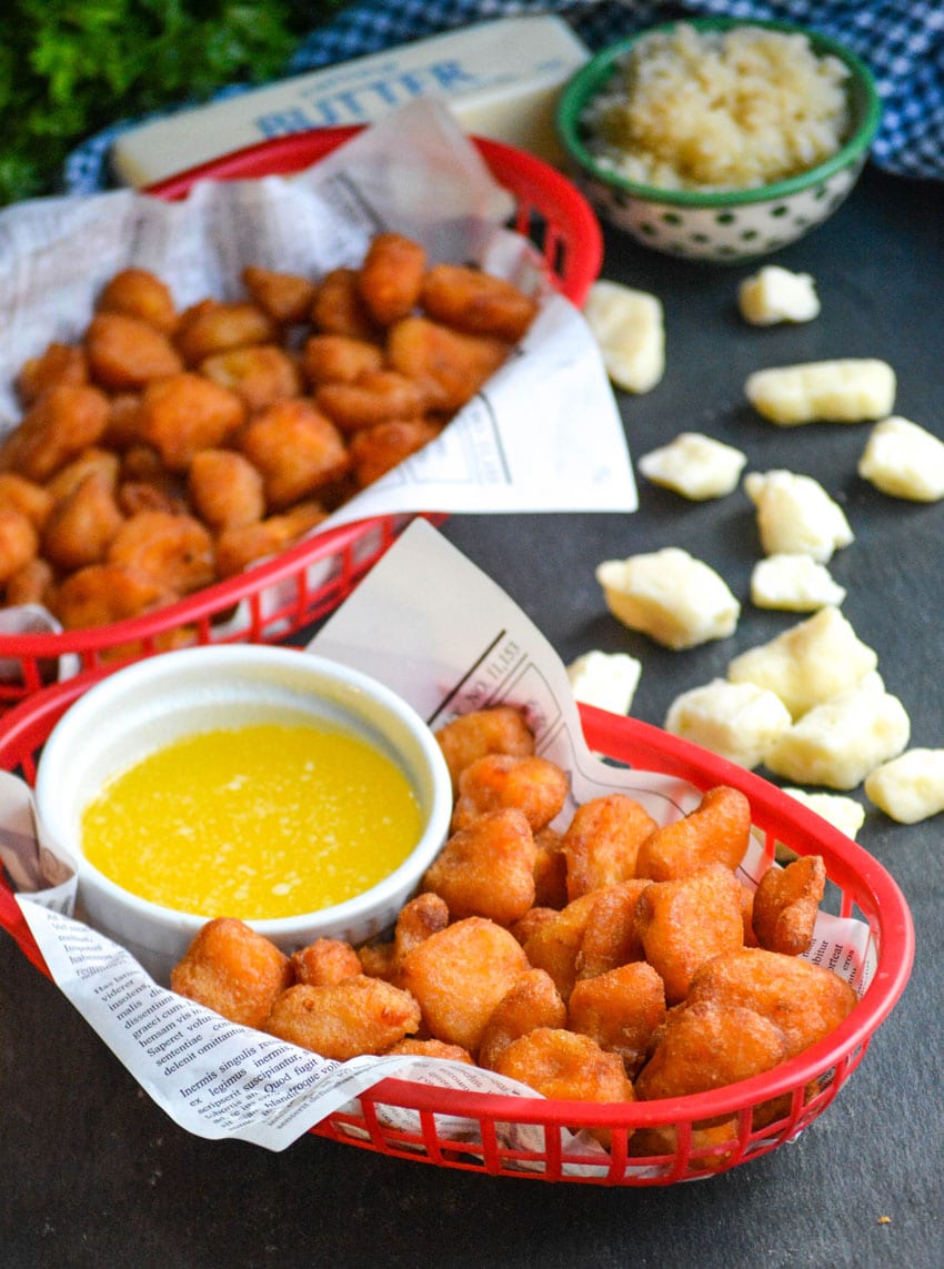 fried cheese curds in a paper lined plastic food basket with a bowl of garlic butter on the side