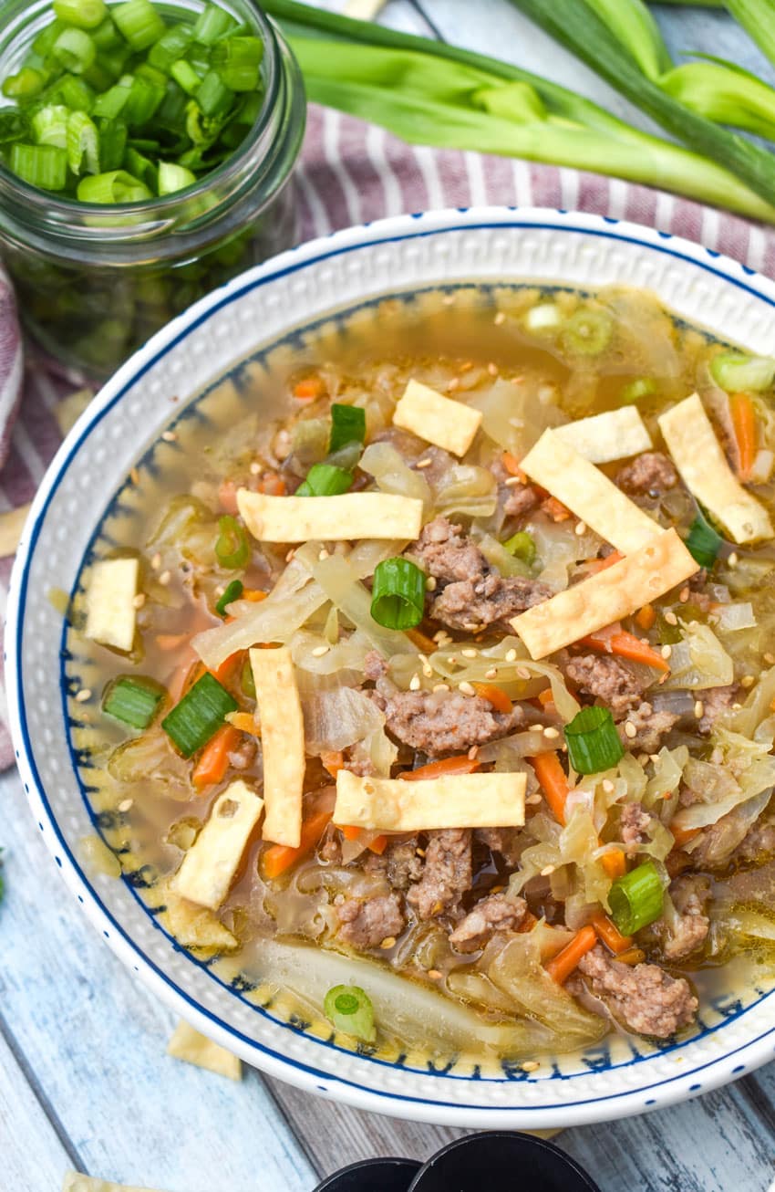 pork egg roll soup topped with crispy wonton strips in a white bowl