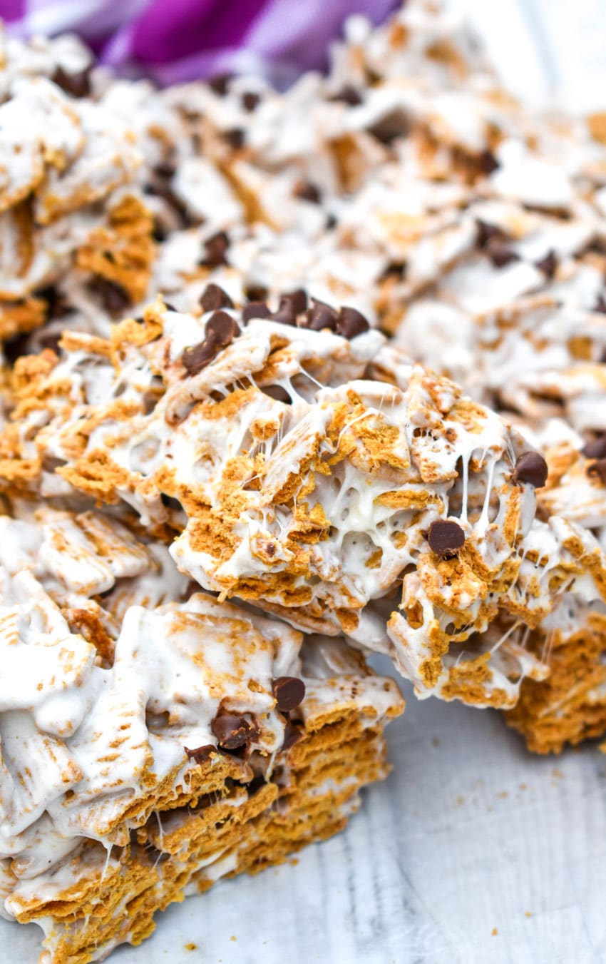 a bitten s'mores cereal bar resting on another cereal on top of a wooden table