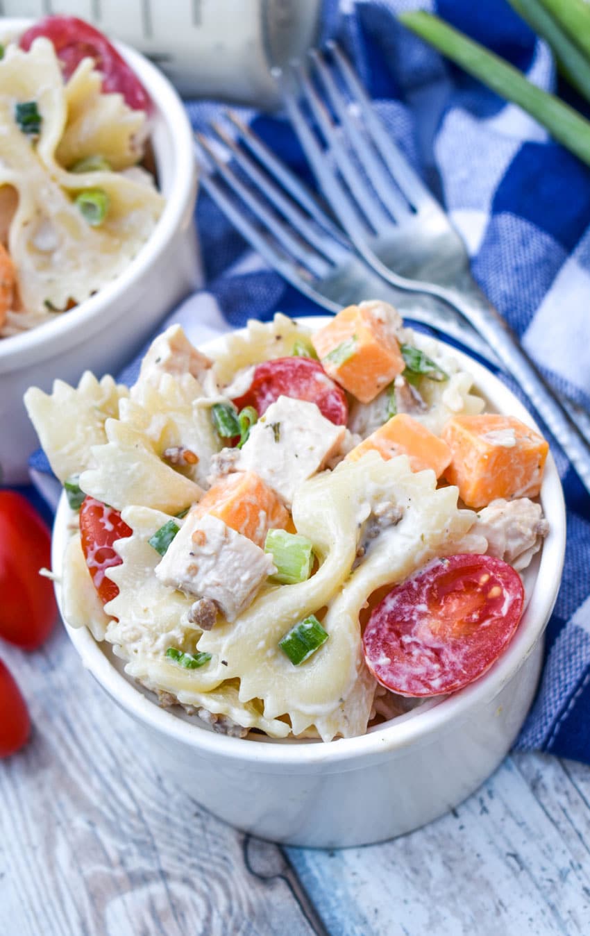 chicken bacon ranch pasta salad in two small white bowls with fresh cherry tomatoes on the side