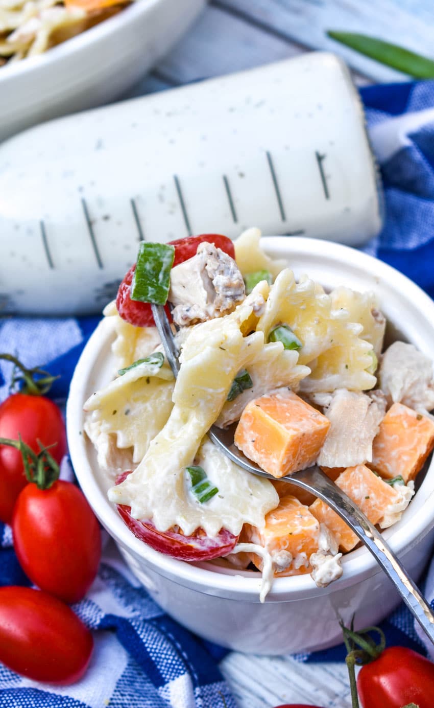 a silver fork scooping chicken bacon ranch pasta salad out of a small white bowl