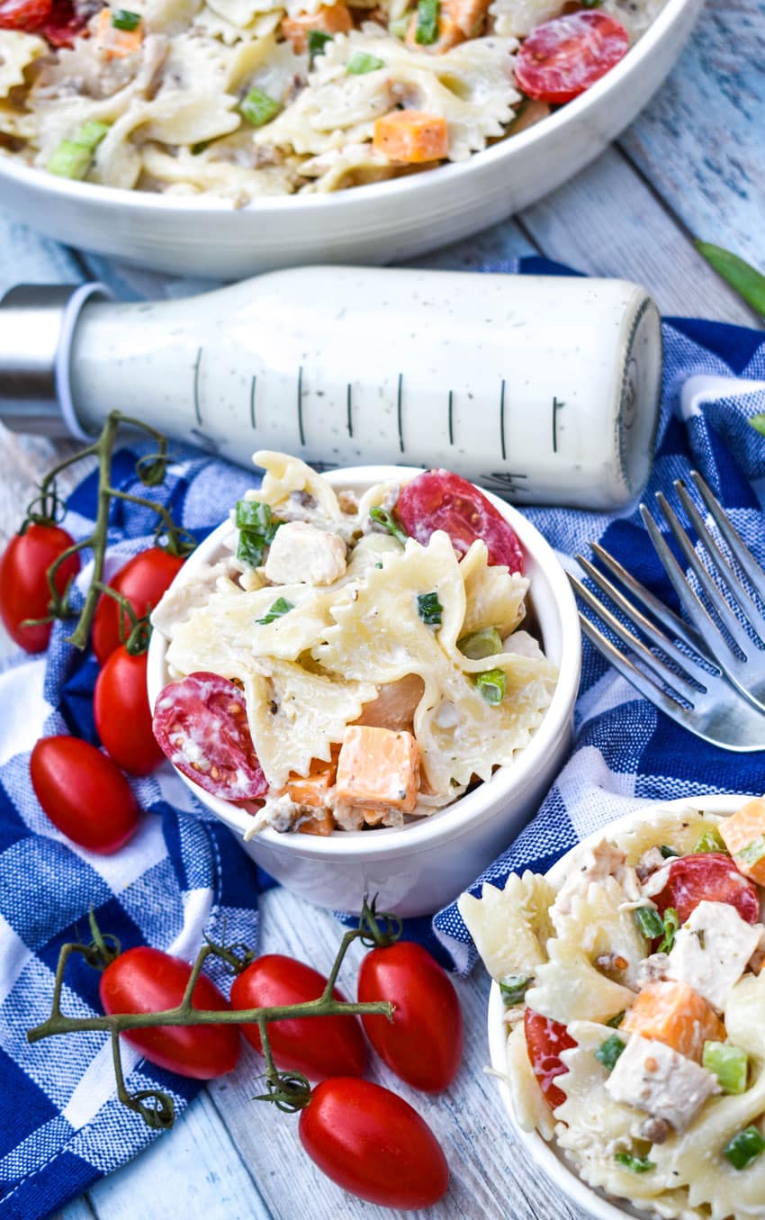 chicken bacon ranch pasta salad in two small white bowls with fresh cherry tomatoes on the side