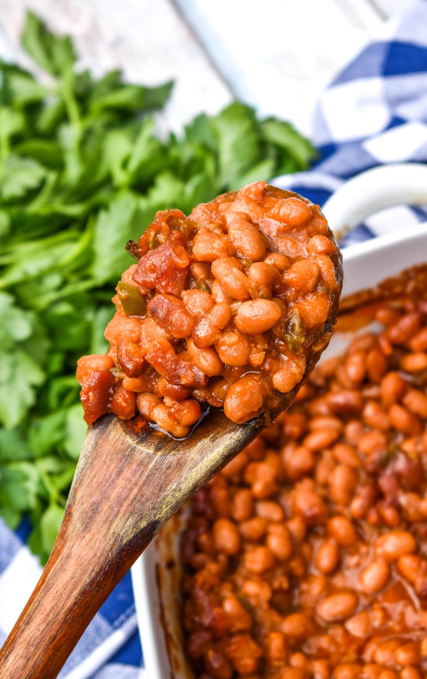 a wooden spoon holding up a scoop of the best canned baked beans recipe