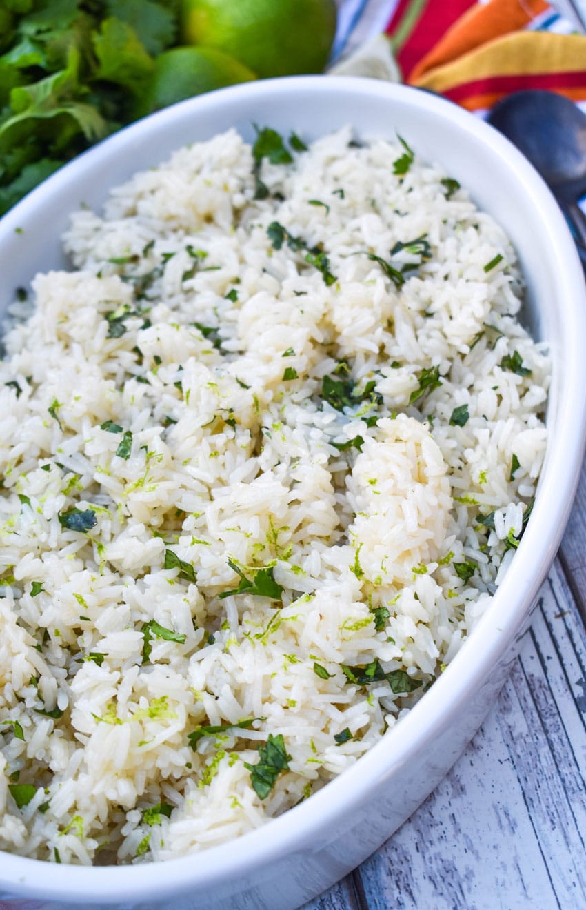 instant pot cilantro lime rice in a white serving bowl with sliced limes on the side