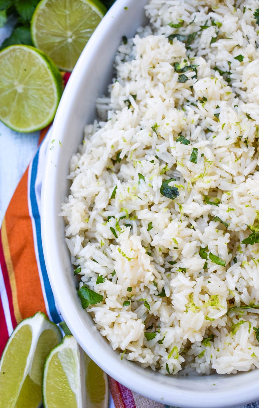 instant pot cilantro lime rice in a white serving bowl with sliced limes on the side