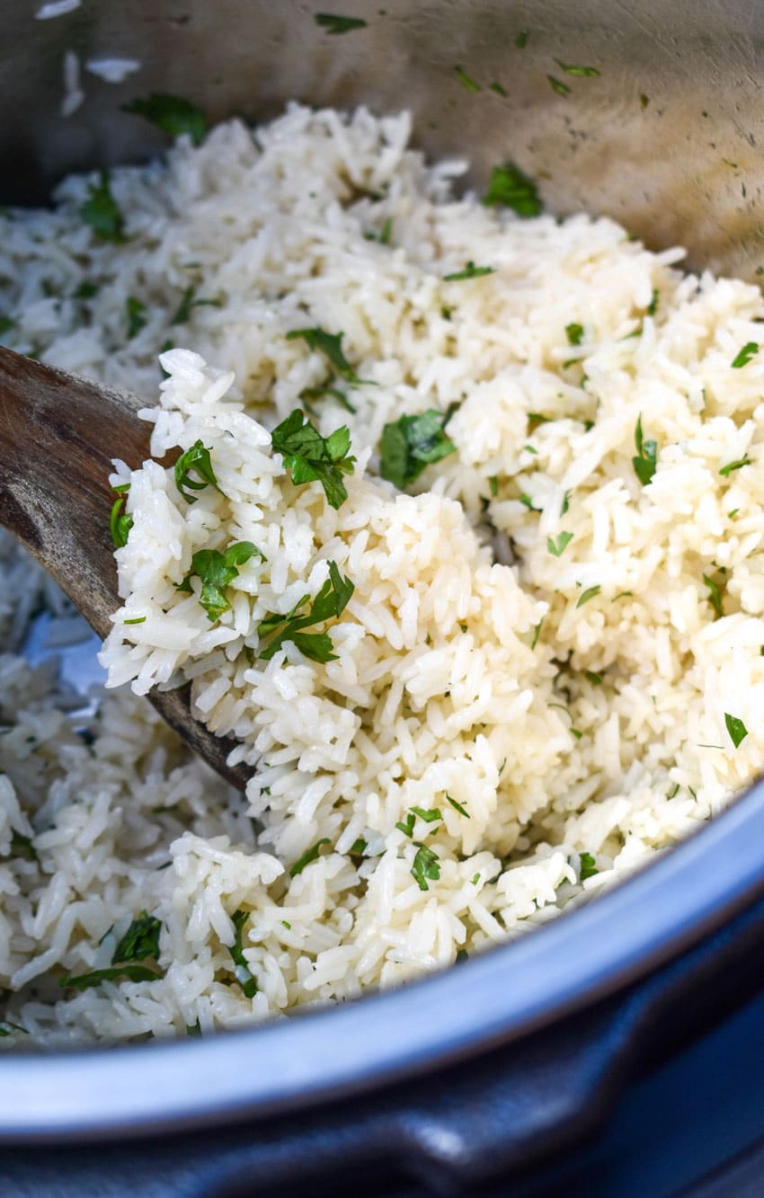 a wooden spoon scooping cilantro lime rice out of an instant pot