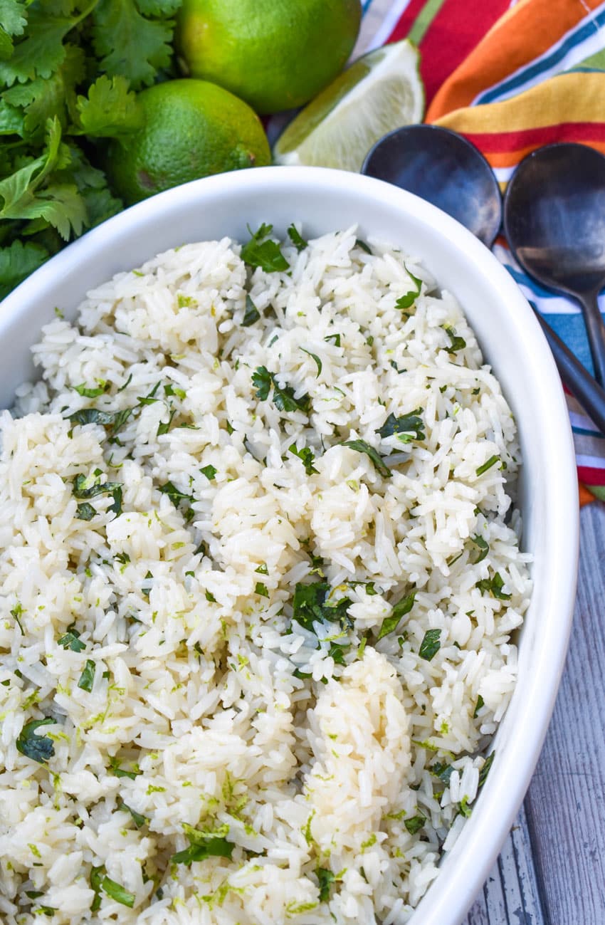 instant pot cilantro lime rice in a white serving bowl with sliced limes on the side