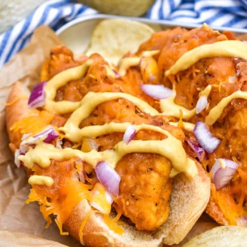 two southern bird dog sandwiches topped with drizzled honey mustard and diced red onion on a parchment paper lined metal serving tray