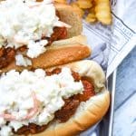 two carolina slaw dogs on a news paper lined metal serving tray with crinkle cut french fries on the side