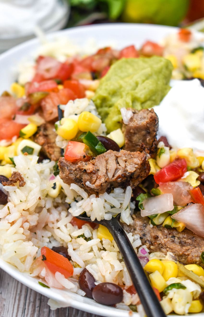 a black fork holding up a scoop of homemade chipotle burrito bowl recipe