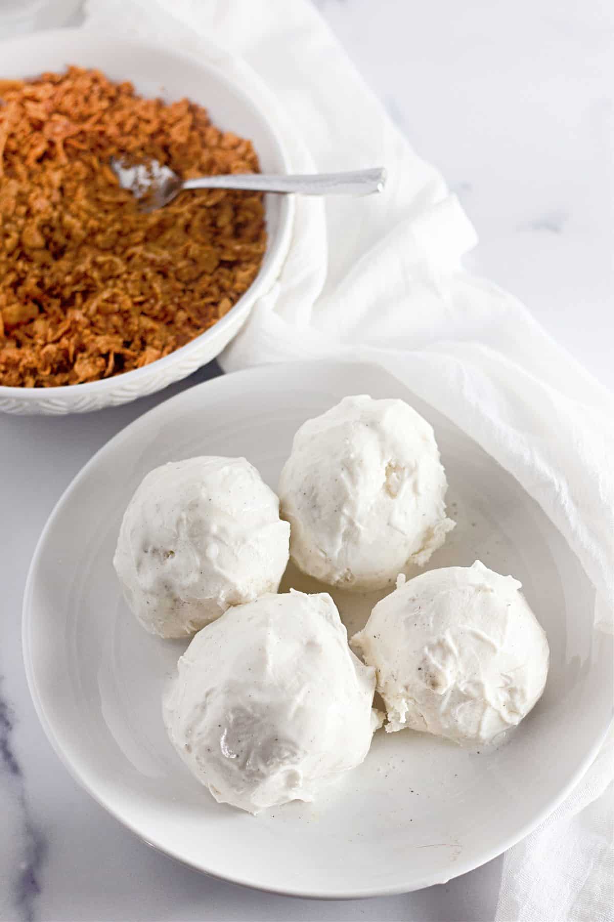 four balls of vanilla ice cream sitting on a small white plate