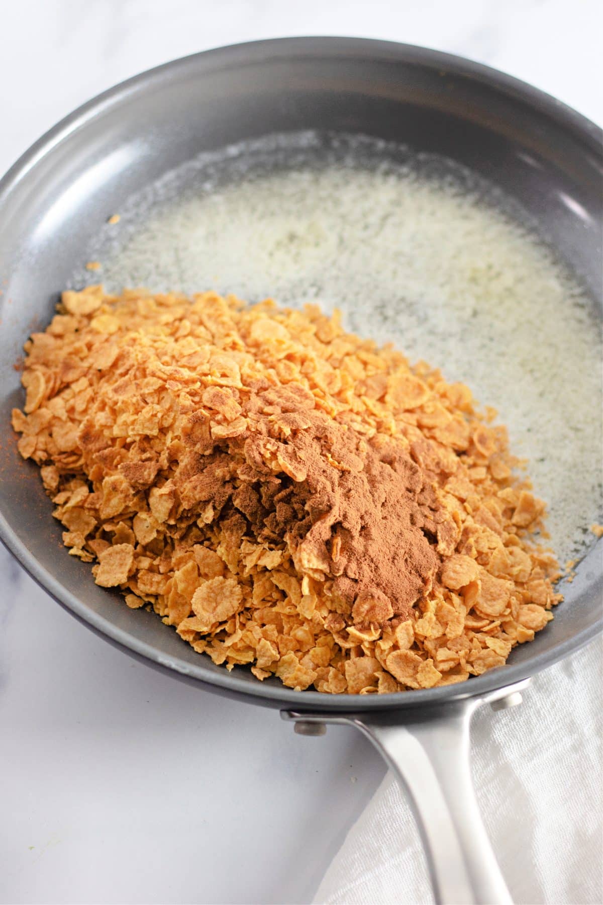 cornflakes and seasoning in a skillet filled with melted butter