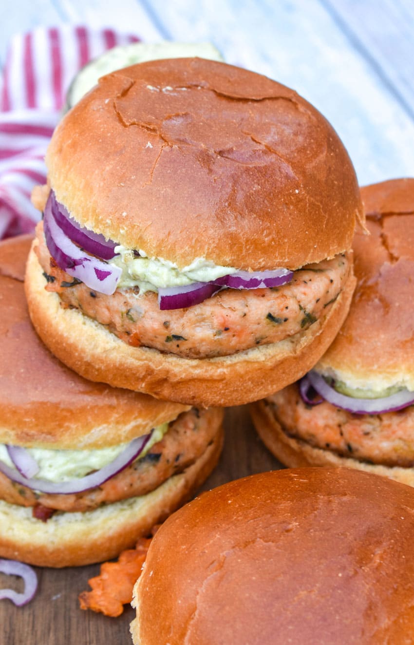 a stack of grilled salmon burgers on a wooden cutting board