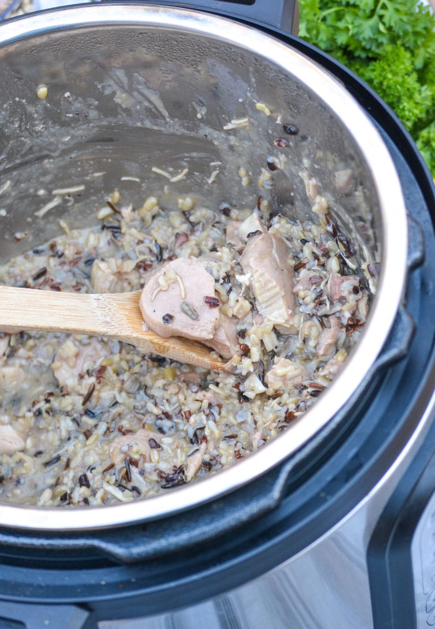 a wooden spoon scooping lemon chicken and wild rice out of an instant pot
