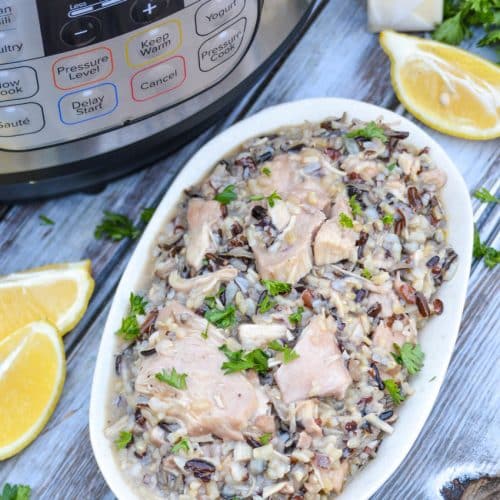 lemon chicken and wild rice in a small serving bowl with lemon wedges on the side and an instant pot in the background