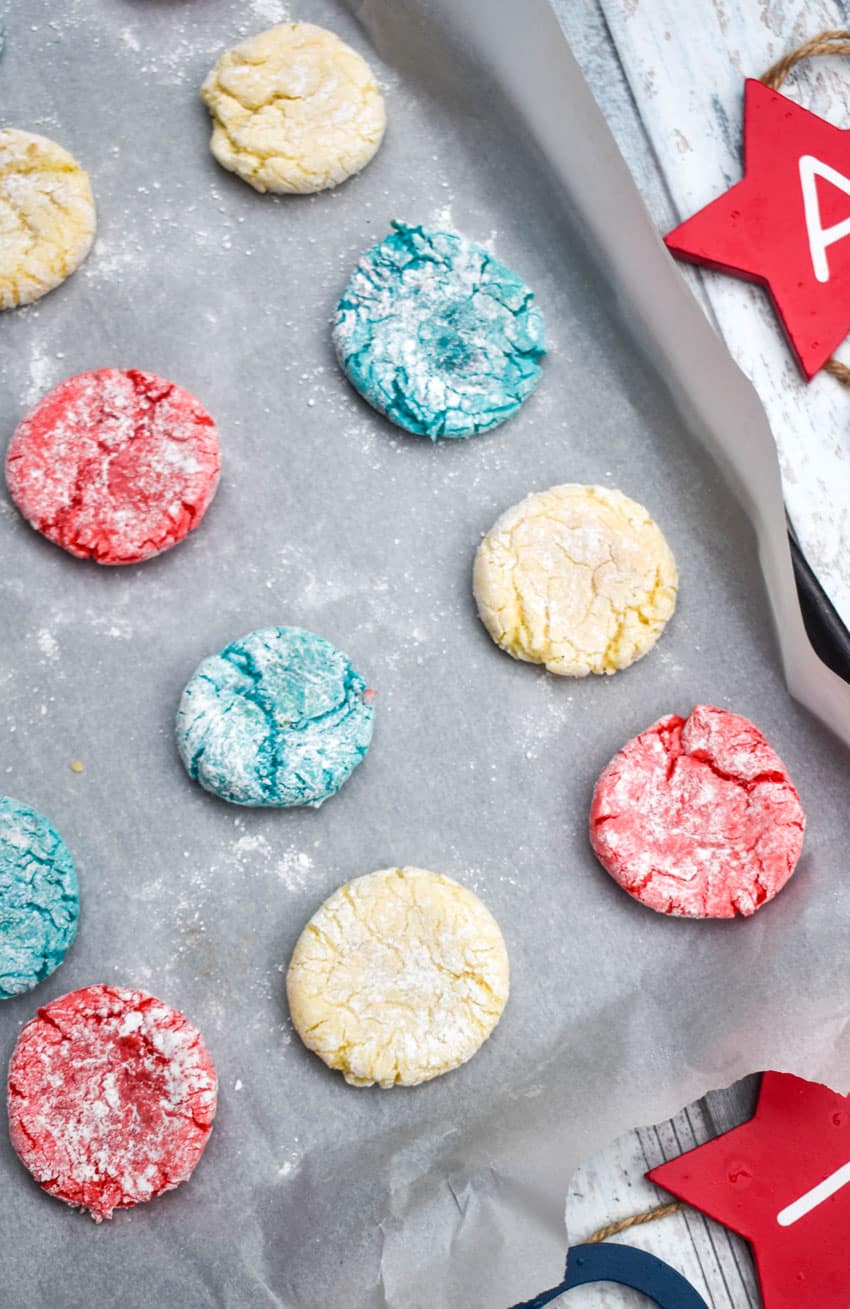 red white and blue crinkle cookies in rows on a parchment paper lined baking sheet