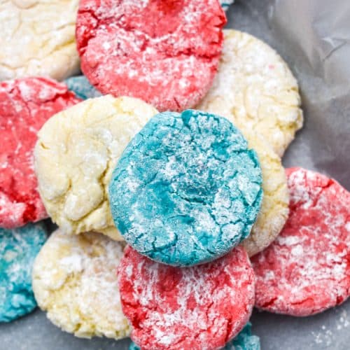 red white and blue crinkle cookies in a pile in the corner of a parchment paper lined baking sheet