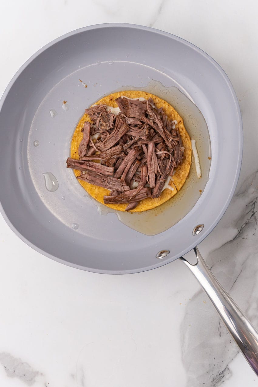 a birria taco in oil in a large skillet