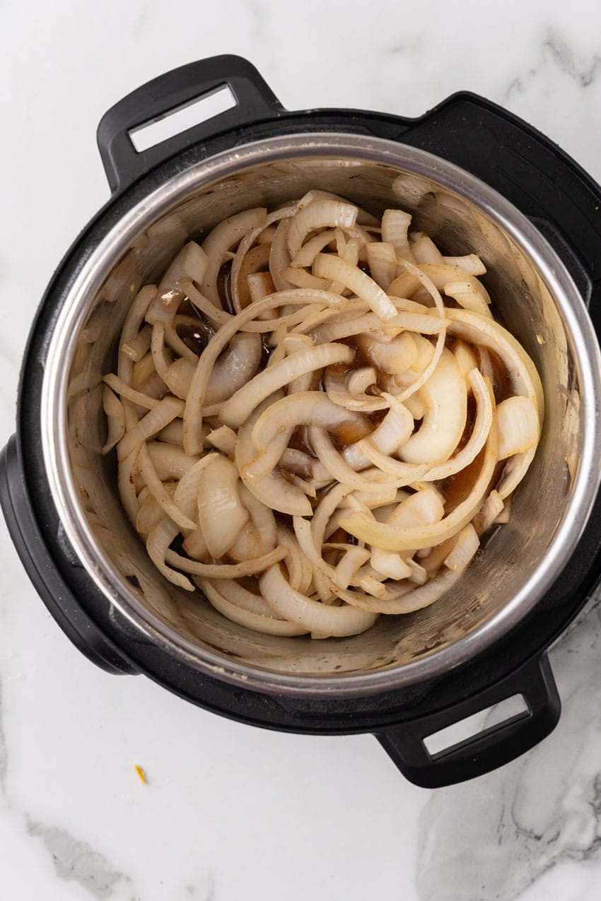 onions and garlic sauteeing in the bowl of an instant pot