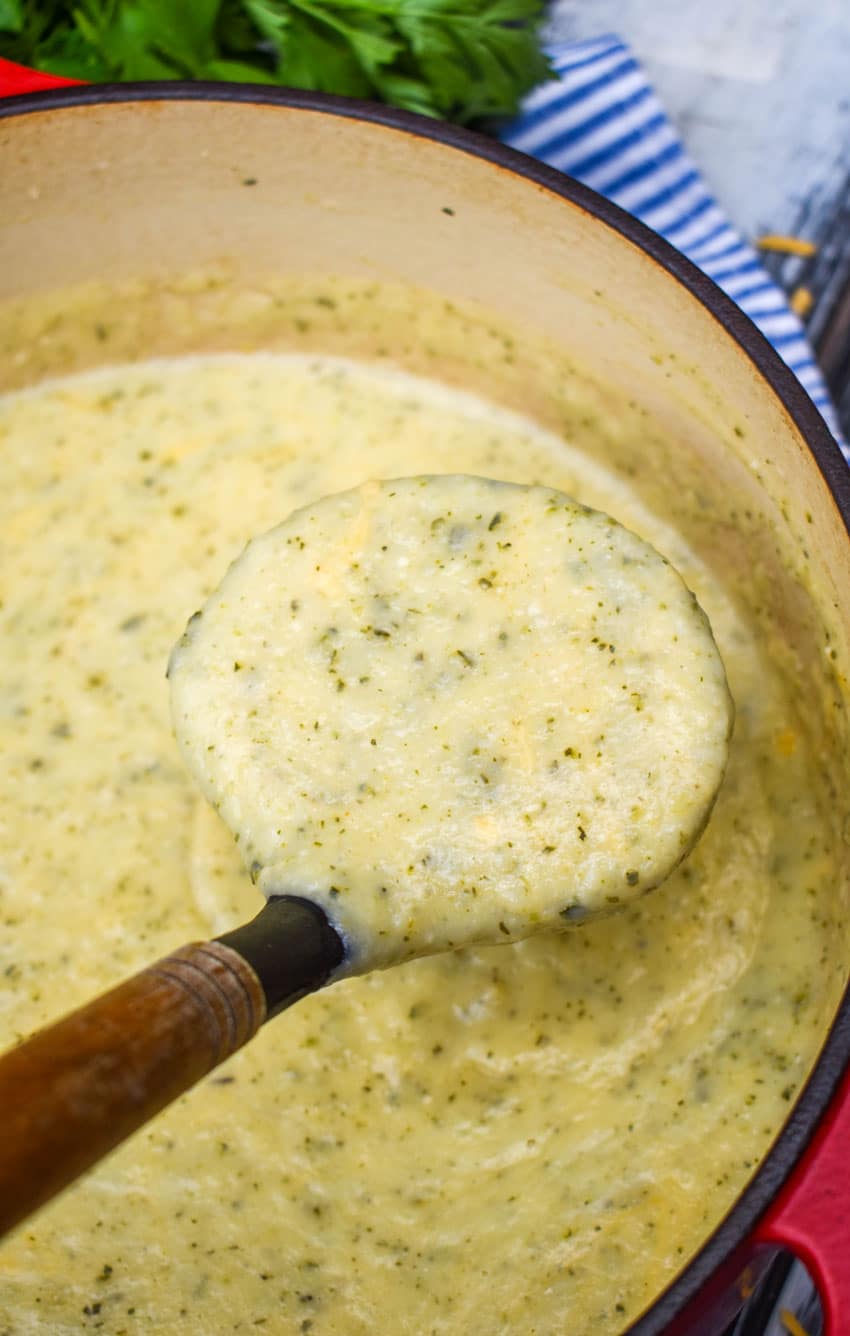 a ladle holding up a scope of thick and creamy zucchini soup