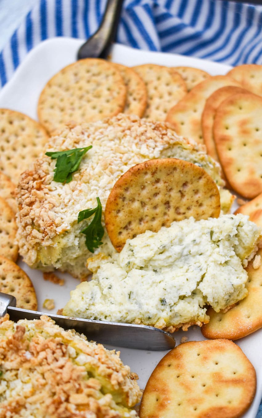 a cracker dipping into crispy baked boursin cheese on a white platter