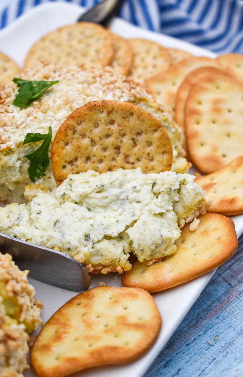 a cracker dipping into crispy baked boursin cheese on a white platter