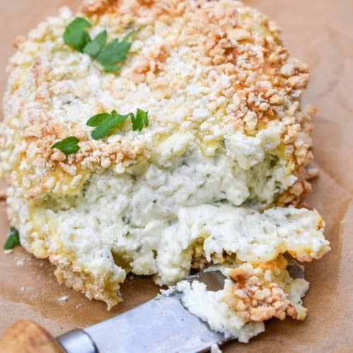 A CHEESE SPREADER CUTTING INTO CRISPY BAKED BOURSIN CHEESE