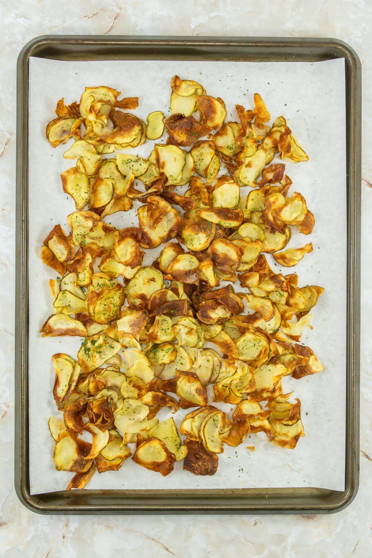 crispy air fried potato chips on a parchment paper lined baking sheet