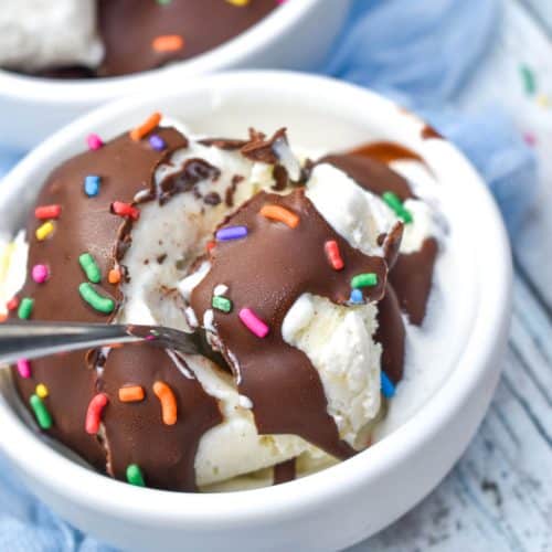 a silver spoon scooping chocolate coated ice cream out of a small white bowl
