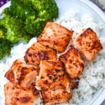 lemon garlic butter air fryer salmon bites over steamed white rice next to cooked broccoli on a white plate