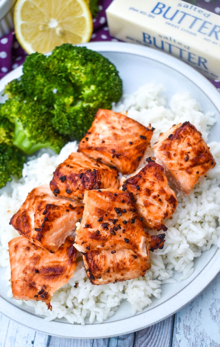 lemon garlic butter air fryer salmon bites over steamed white rice next to cooked broccoli on a white plate
