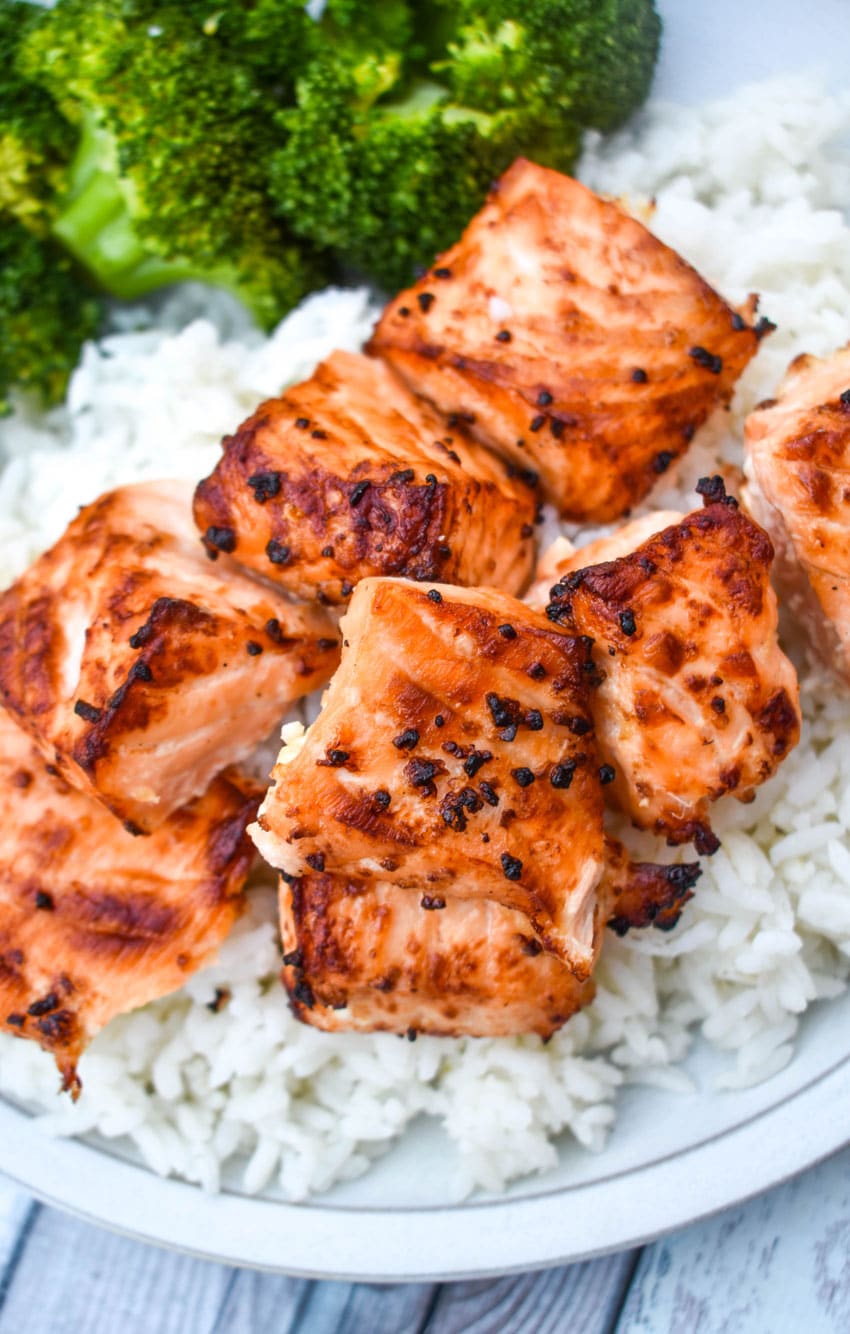 lemon garlic butter air fryer salmon bites over steamed white rice next to cooked broccoli on a white plate