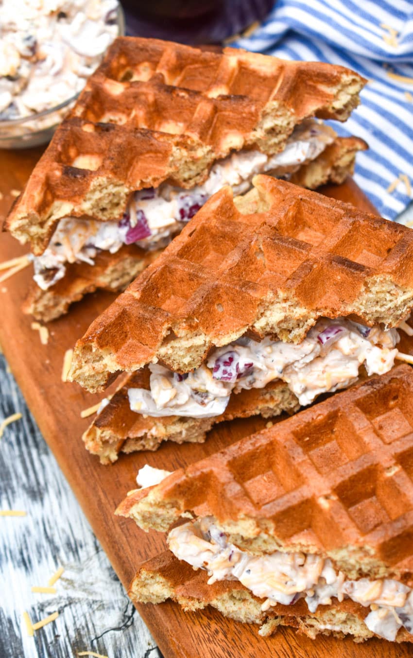 maple bacon chicken salad in between sliced waffles on a wooden cutting board