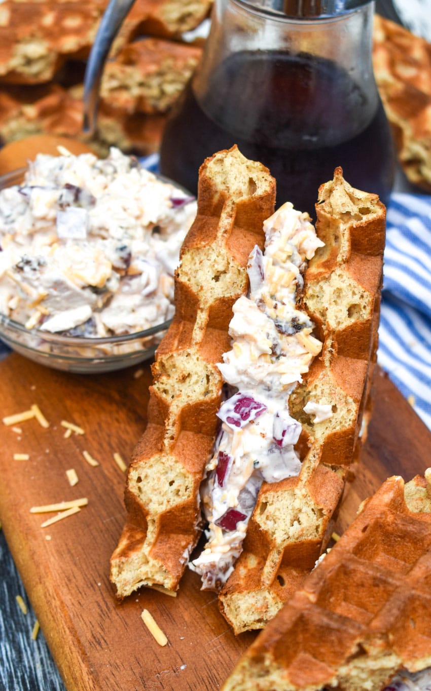 maple bacon chicken salad in a waffle sandwich on a wooden cutting board
