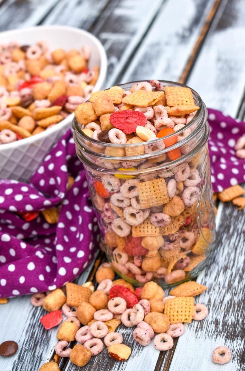 peanut butter and jelly trail mix in a small glass jar on a wooden table