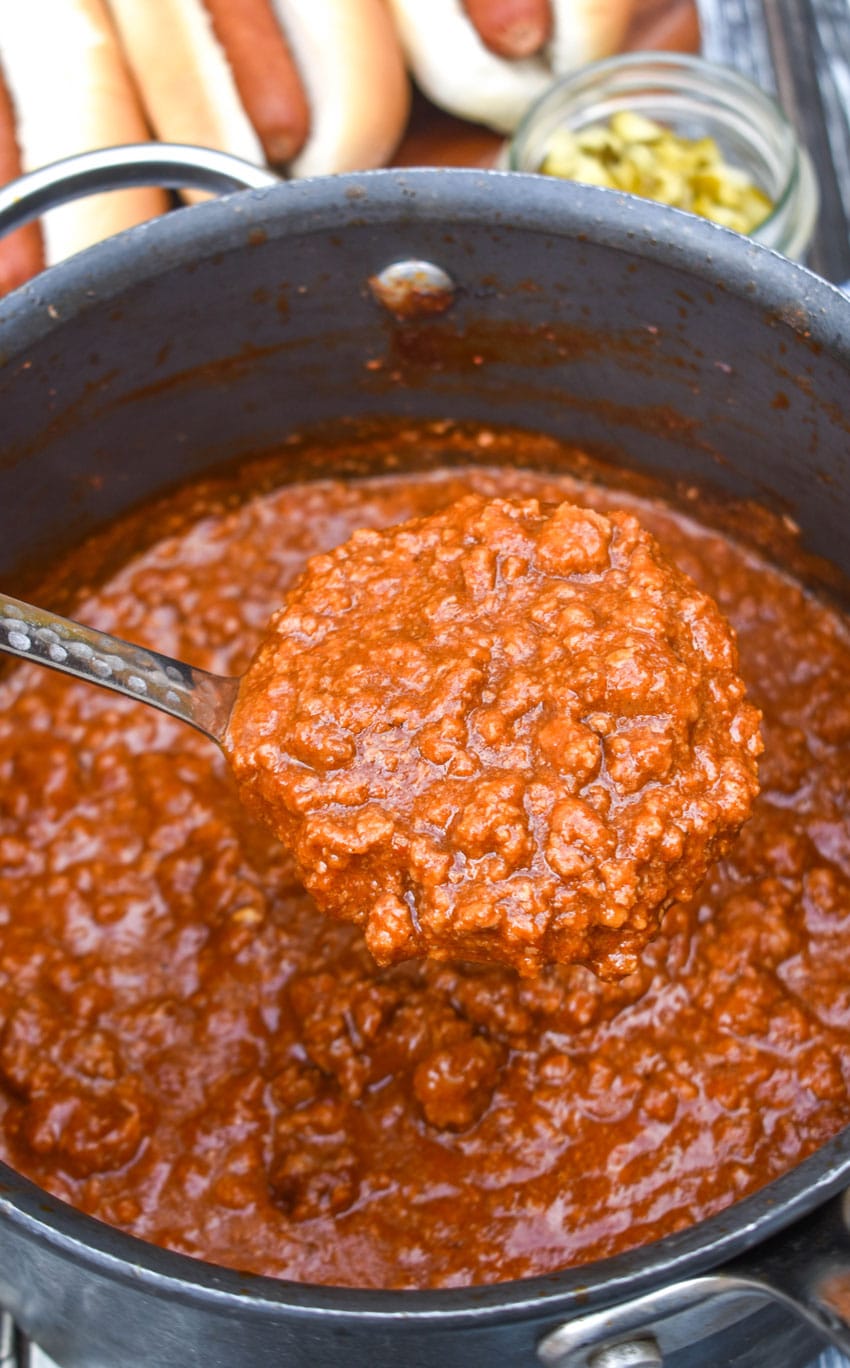a silver ladle scooping easy hot dog chili out of a black pot