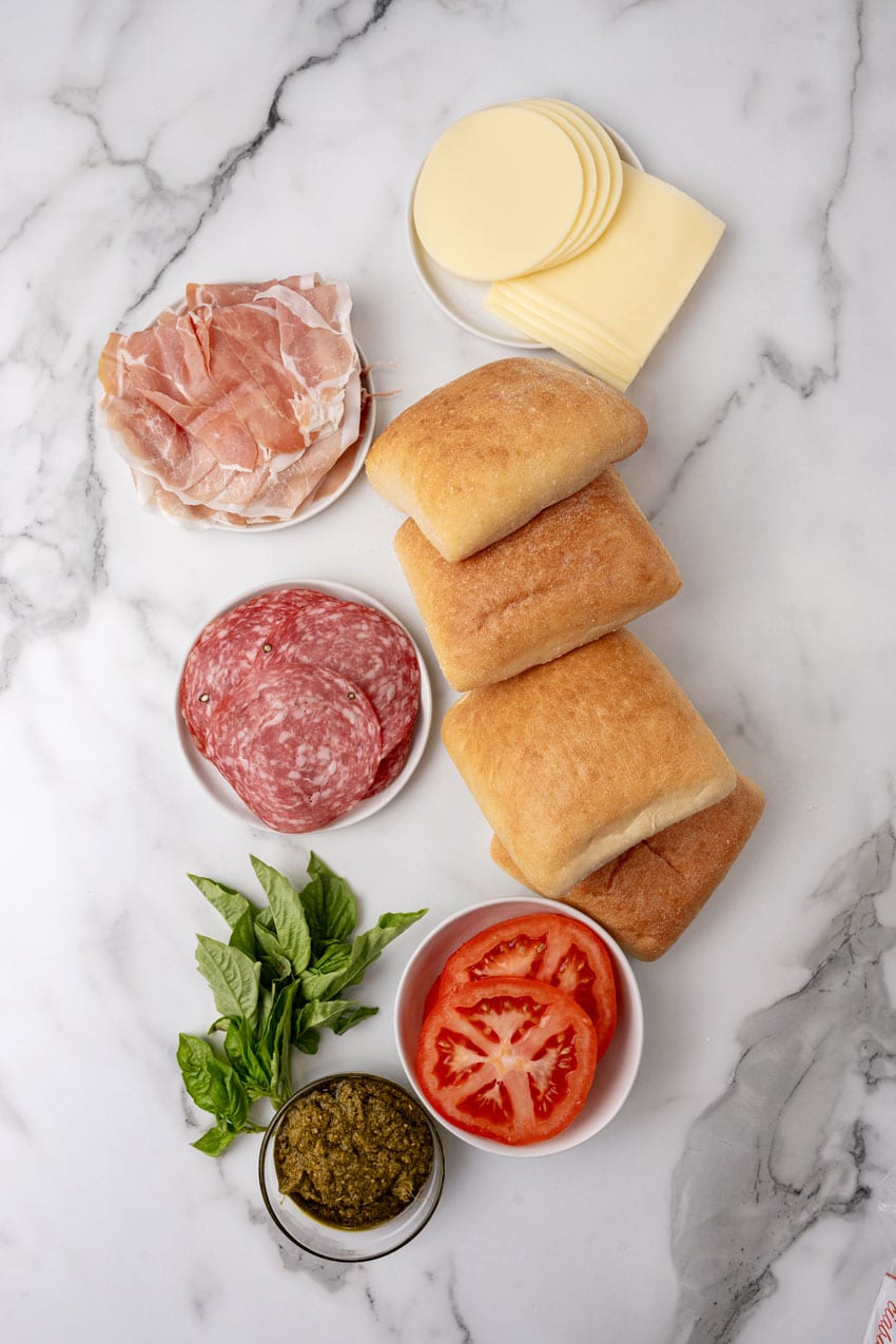 an overhead image showing the measured ingredients needed to make a batch of pressed italian picnic sandwich