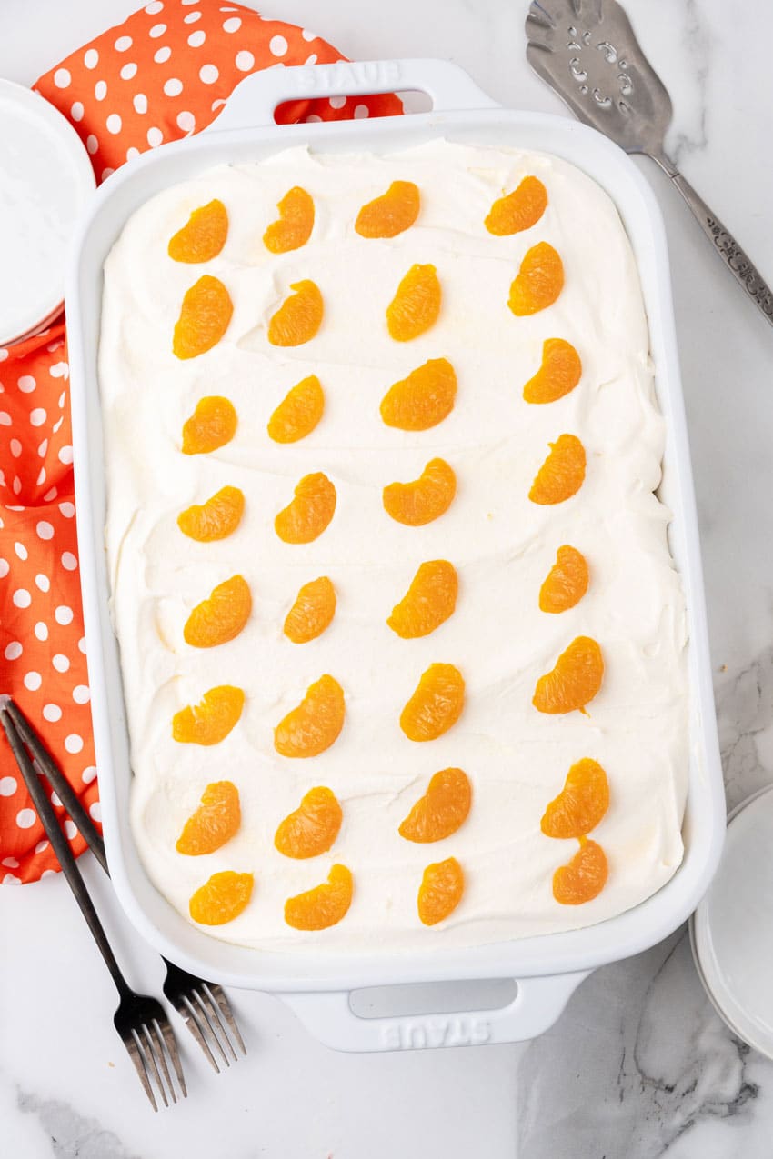 an orange creamsicle poke cake in a white baking dish