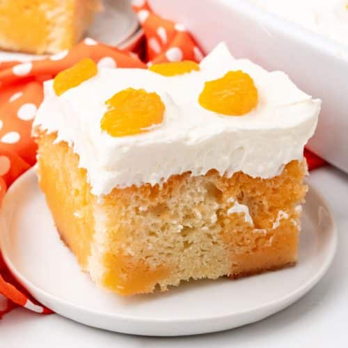a slice of orange creamsicle poke cake on a small white dessert plate
