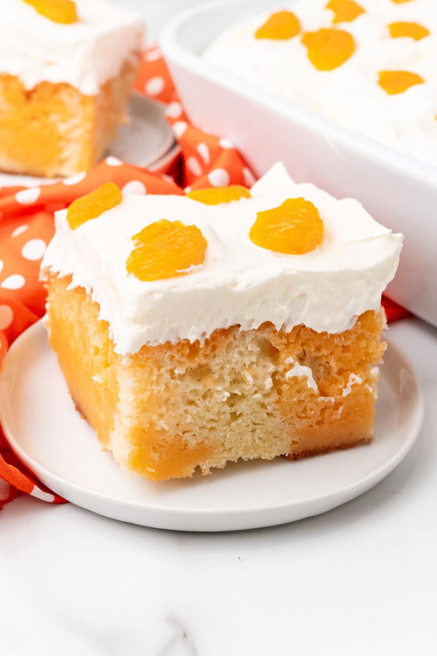 Orange Creamsicle Poke Cake a slice of orange creamsicle poke cake on a small white dessert plate