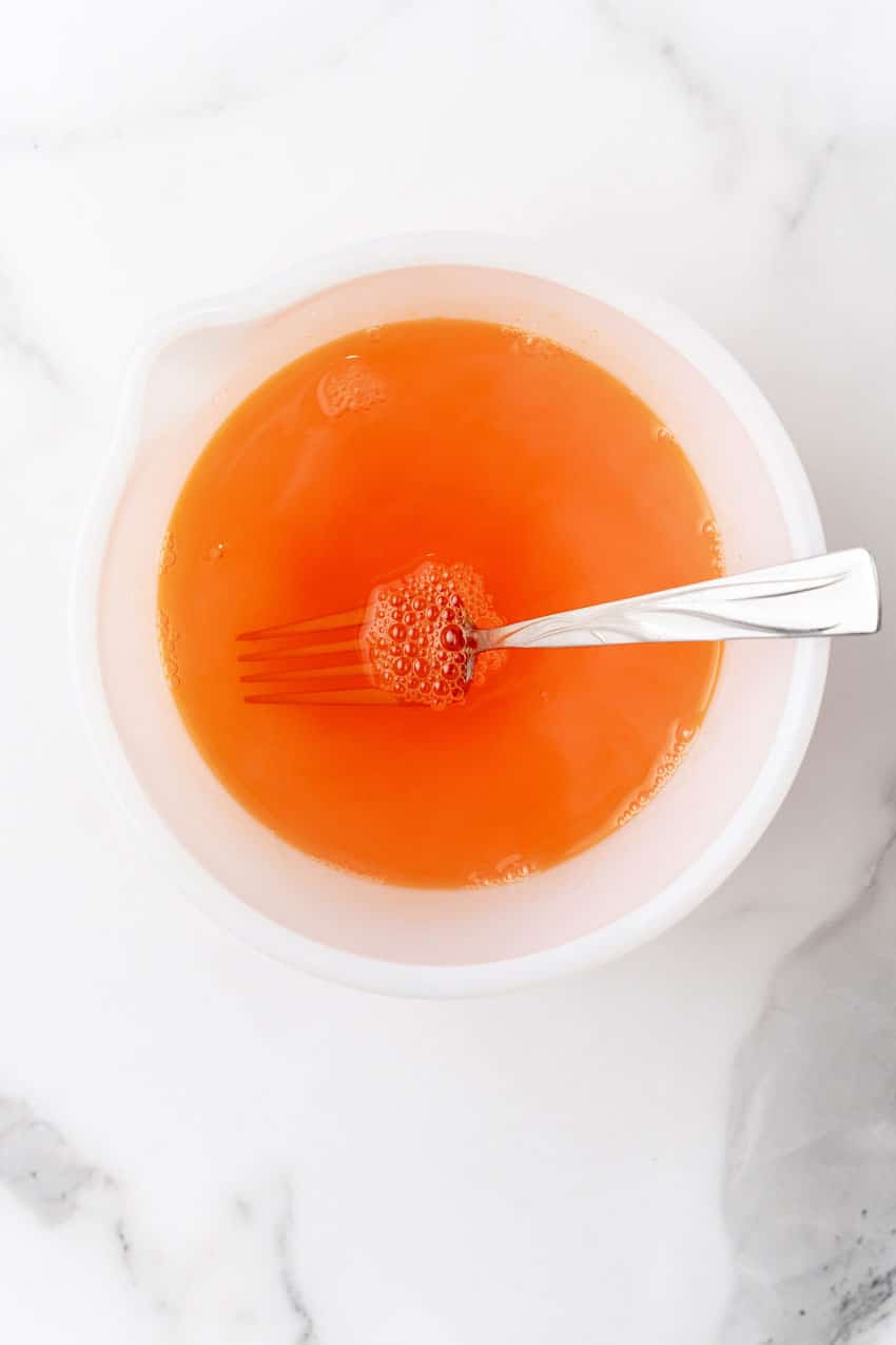 warm orange jello in a white mixing bowl