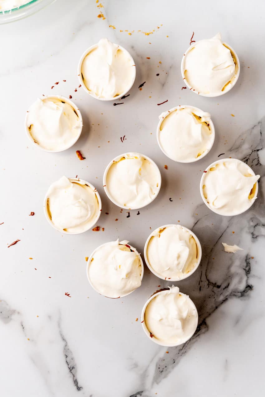 layers of ice cream, chocolate sauce, and crushed graham crackers in a paper cup
