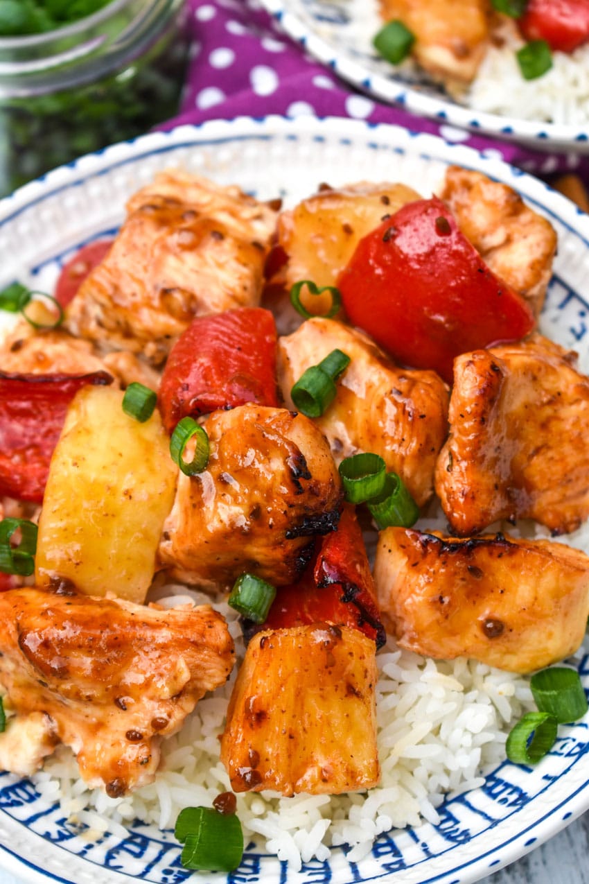 a close up up air fryer pineapple chicken served over steamed white rice in a white bowl