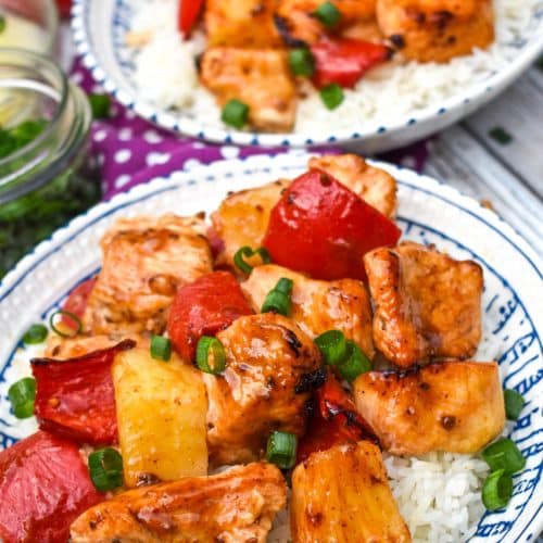 air fryer pineapple chicken over steamed white rice topped with sliced green onions in two white bowls