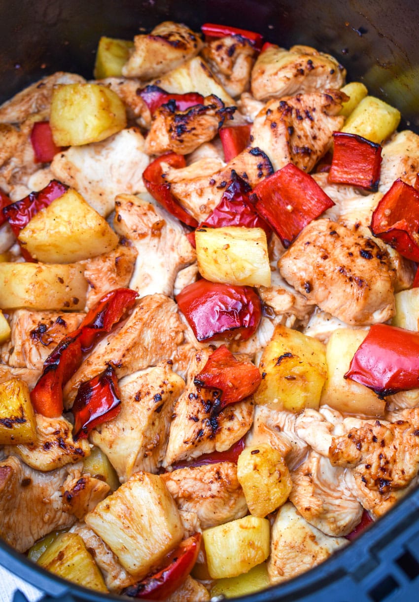 a close up of pineapple chicken in the basket of an air fryer