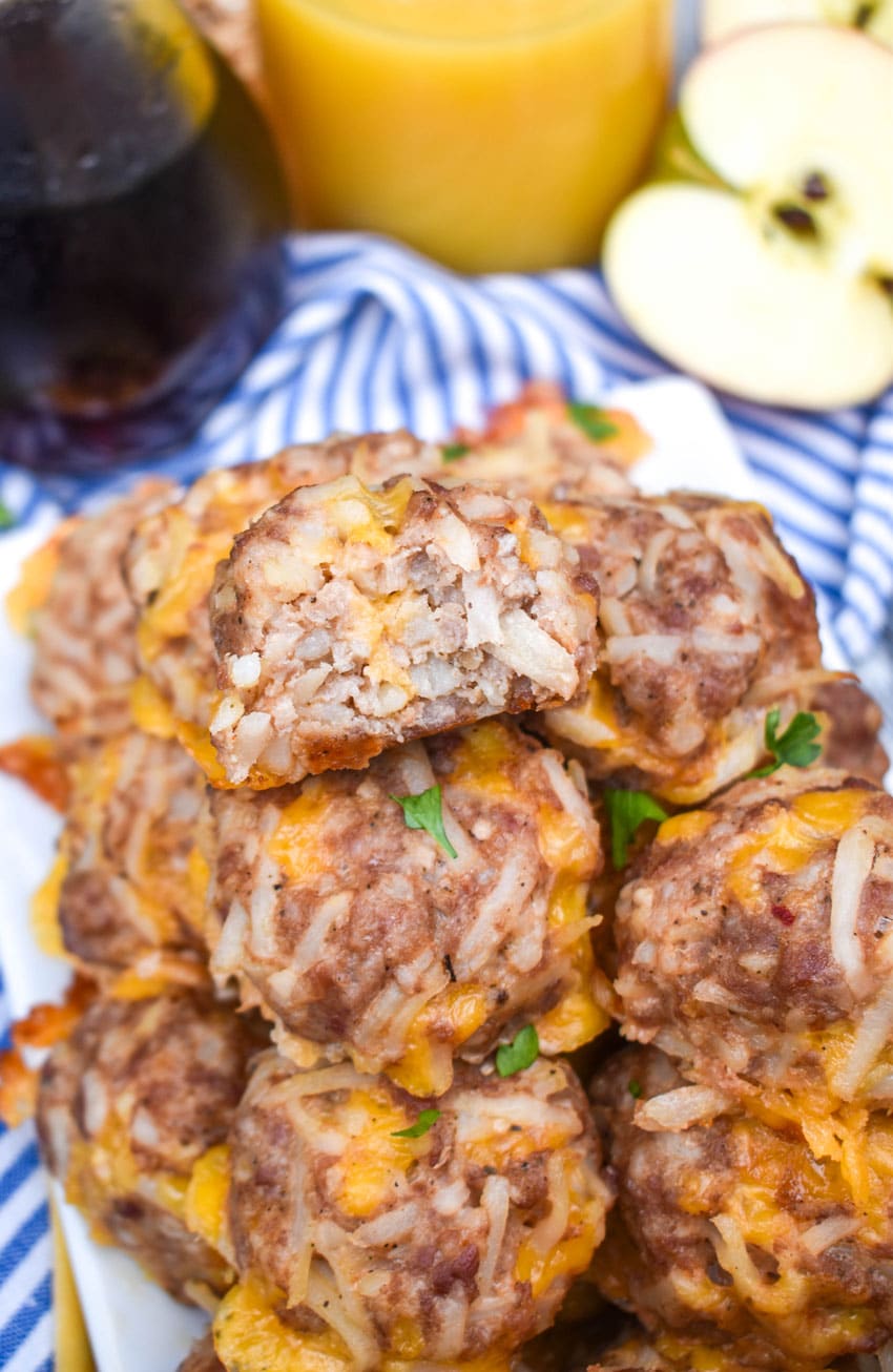 a bitten breakfast sausage ball resting on a pile of sausage balls on a white platter
