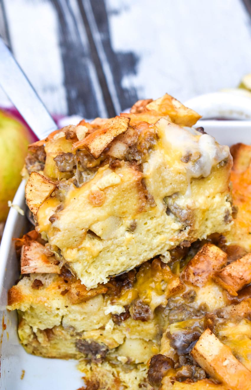 a silver spatula holding up a slice of cheesy sausage apple breakfast bake
