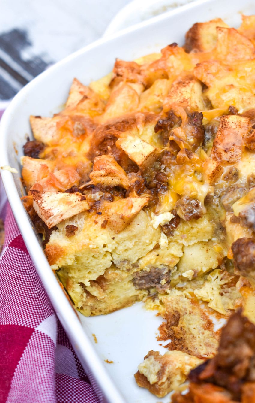 cheesy sausage apple breakfast bake in a white casserole dish with a slice removed to show the layers of filling