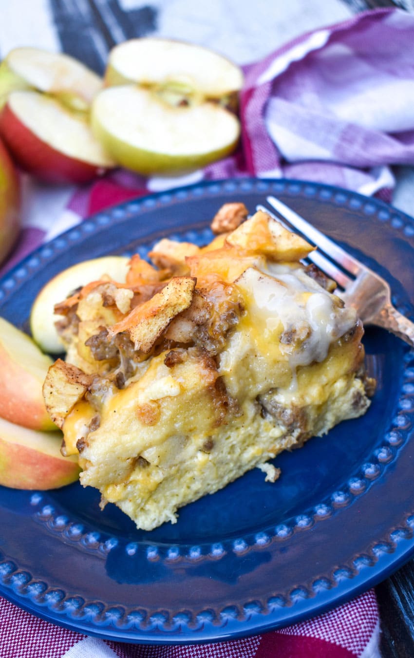 a slice of sausage apple breakfast casserole on a blue plate with a silver fork resting on the side
