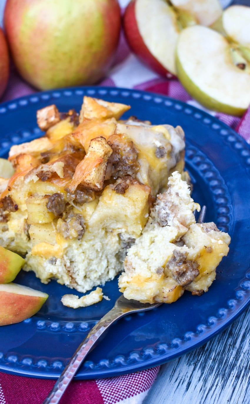 a slice of sausage apple breakfast casserole on a blue plate with a silver fork resting on the side